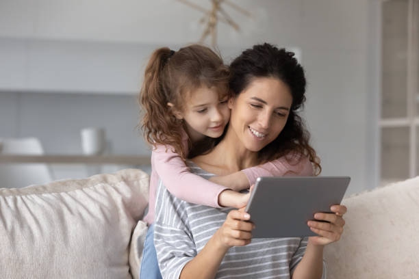 istock Happy small girl and loving mother using tablet. 1358310817