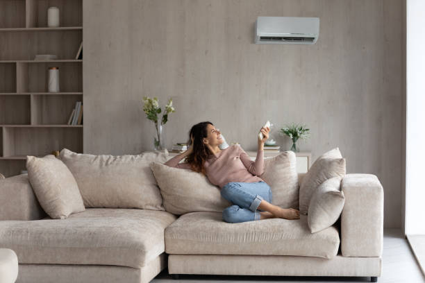 istock Relaxed young hispanic woman turning on air conditioner. 1358310880