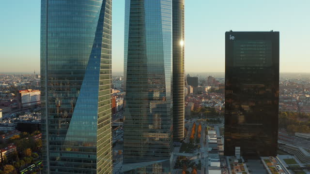 Slide and pan footage of modern buildings in Cuatro Torres Business Area. Glossy glass facades of skyscrapers reflecting surroundings
