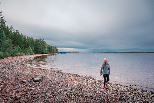 Mujer caminando en la playa y la orilla del lago en el lago Siljan en Dalarna, Suecia photo