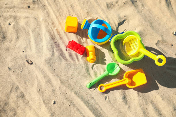 istock Different child plastic toys on sandy beach, flat lay. Space for text 1358320161