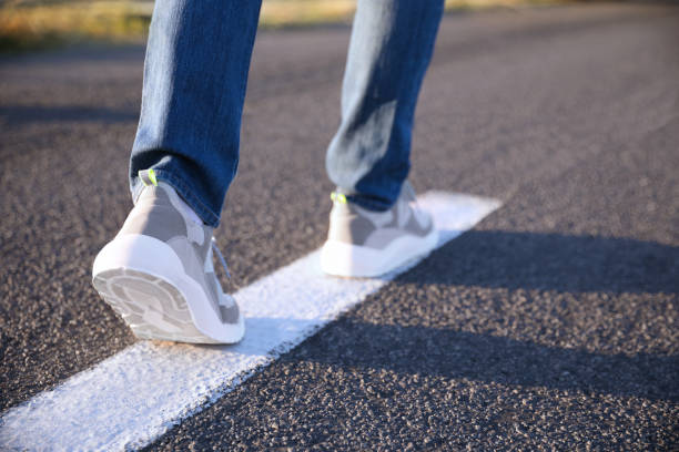 istock Man walking along white line on road, closeup with space for text. Way concept 1358322450