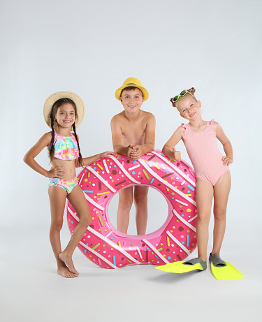 Cute little children in beachwear with bright inflatable ring on white background