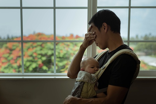 Un padre cansado y estresado sosteniendo a su bebé dormido en casa. Depresión posparto. photo