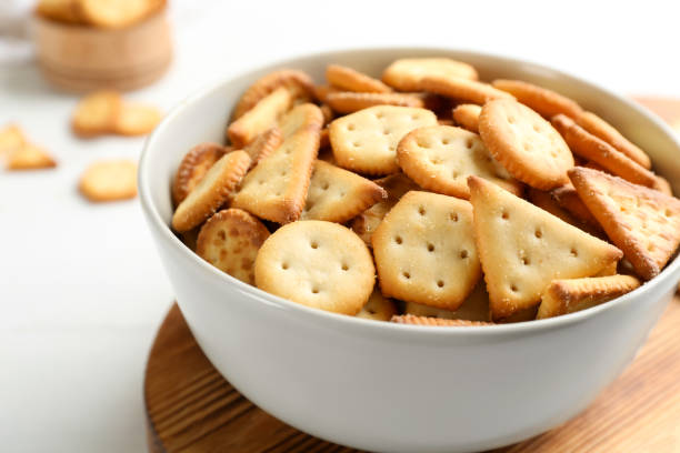 istock Delicious crispy crackers in bowl on white table, closeup 1358324723