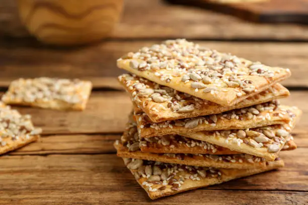 Stack of delicious crackers on wooden table, closeup