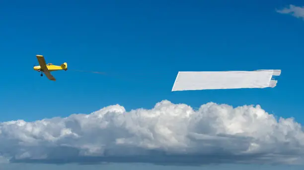 Airplane towing a banner against sky background.