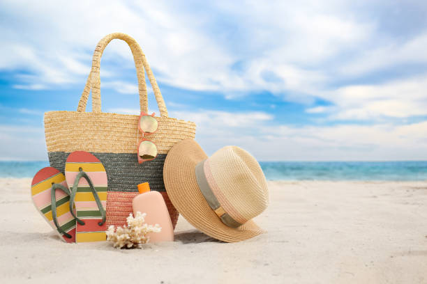 Different stylish beach objects and coral on sand near sea. Space for text Different stylish beach objects and coral on sand near sea. Space for text beach bag stock pictures, royalty-free photos & images