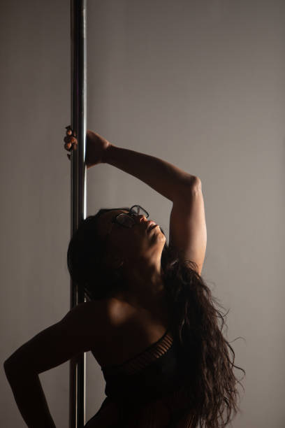 Female pole dancer of color Women of color pole dancing. Pole dance is both exotic and athletic. Strength and grace are required to create beautiful lines and shapes as a pole dancer and aerialist. black pole dancers stock pictures, royalty-free photos & images