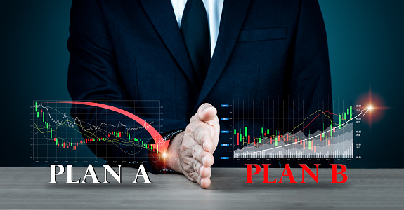 A businessman's hand obstructs PLAN A. PLAN B wording on the table backdrop has been changed. Concepts such as strategy, analysis, marketing, project management, and crisis management
