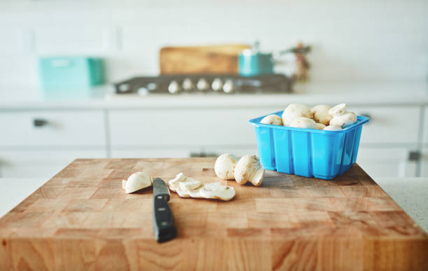 Edible mushrooms being sliced on a chopping board in a bright modern kitchen