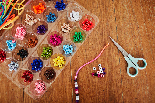 Plastic egg box being used to store plastic beads for children's crafts. Recycling and making friendship bracelets.