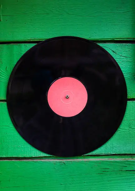 Old Vinyl Record on the Green Planks Background