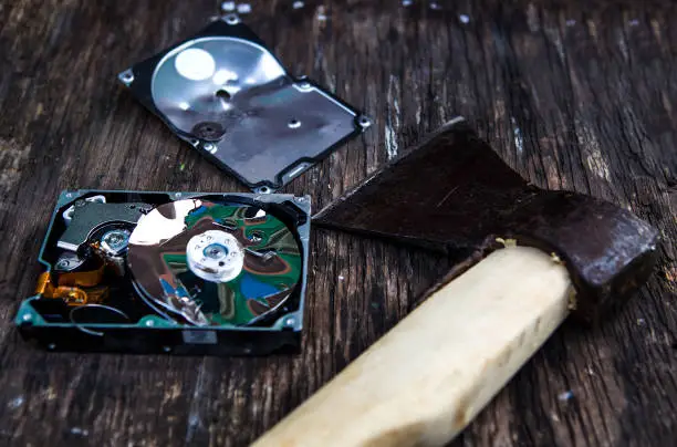 Crushed Hard Disk Drive and Axe on the Old Wooden Table