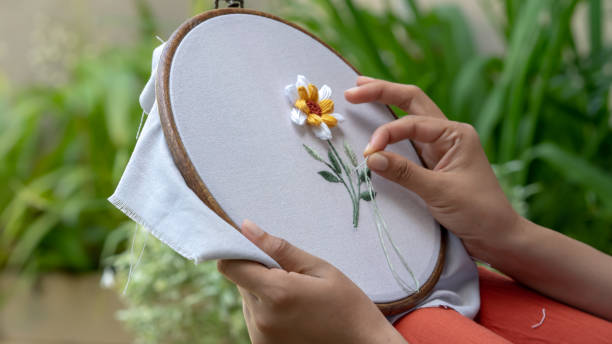 女性はリラックスするための布の上に花を刺繍手 - embroidery sewing needle craft ストックフォトと画像