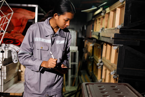 mulher asiática de 20 anos em uniforme cinza conta itens no depósito. serviço de manutenção - garage organization house basement - fotografias e filmes do acervo