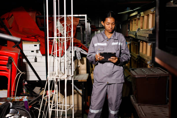 mulher asiática de 20 anos em uniforme cinza conta itens no depósito. serviço de manutenção - garage organization house basement - fotografias e filmes do acervo