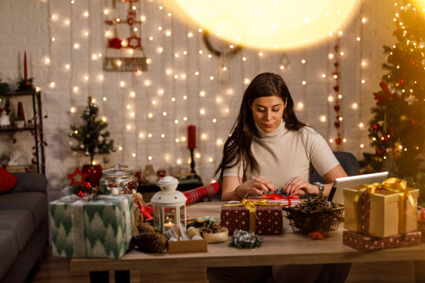 istock Young woman putting final touches on a Christmas gift she is wrapping 1358363362
