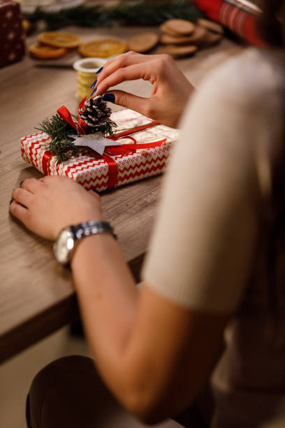 istock Selective focus shot of woman adding decorations on a Christmas gift she is preparing 1358363445