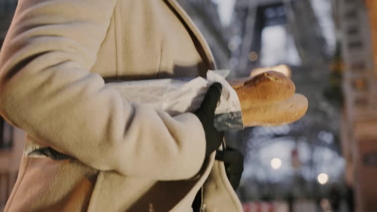 SLO MO French woman carries baguettes down the street along the Eiffel Tower