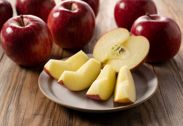 istock Cut apples on a plate against a wooden background. 1358367089