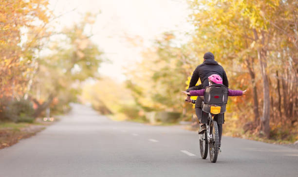 Dad is riding a bicycle with his children Dad is riding a bicycle with his children on an autumn road forward athlete stock pictures, royalty-free photos & images