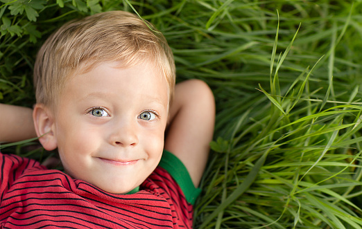 A happy baby lying on the grass and smiling