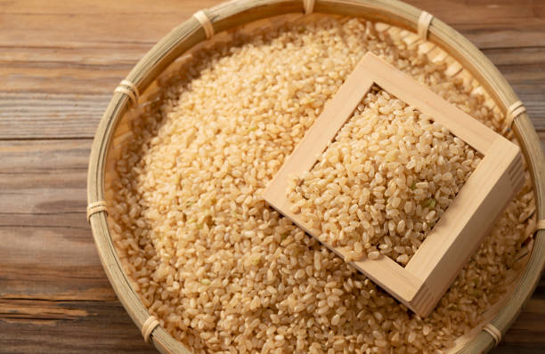 arroz integral en una caja de madera sobre un fondo de madera. - brown rice fotos fotografías e imágenes de stock
