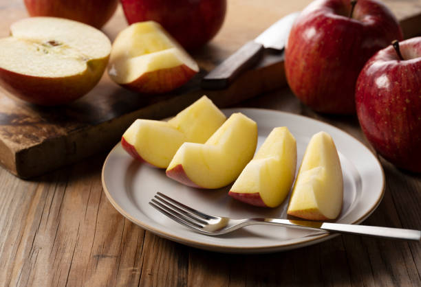 istock Cut apples on a plate against a wooden background. 1358367386