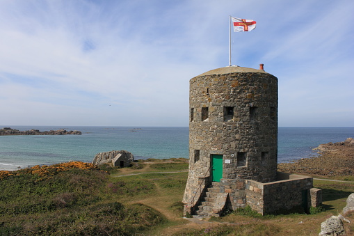A loophole tower on the coast of Guernsey with the Guernsey Flag flying