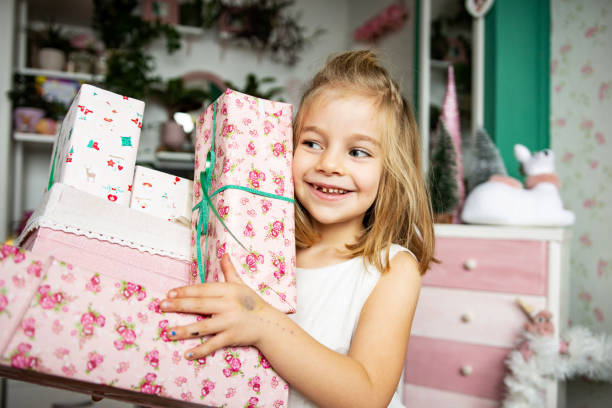 istock Cute girl (5-6) holding Christmas gift boxes, smiling 1358374982