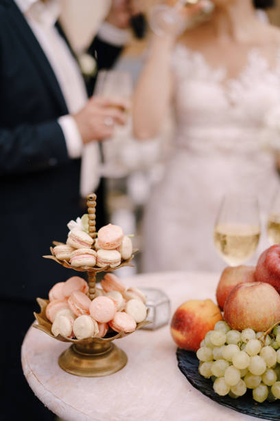 plato de pasteles de macarrones se encuentra junto a un tazón de fruta en el fondo de los recién casados - wedding cake newlywed wedding cake fotografías e imágenes de stock