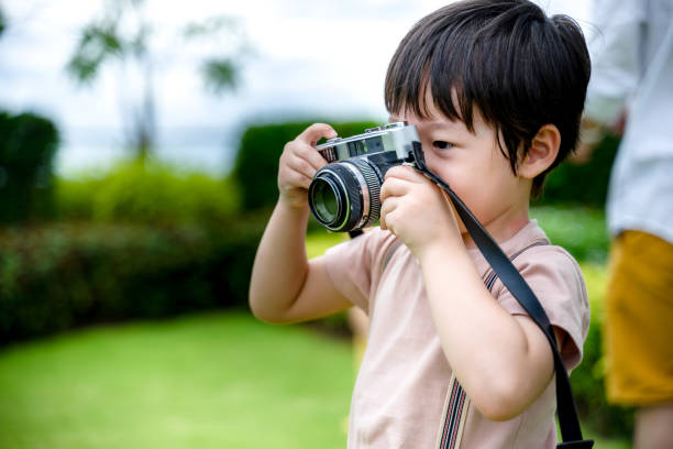 istock little boy fun and enjoying learning professional photographer taking a picture using a vintage retro film, Educational and learning concept. 1358385122