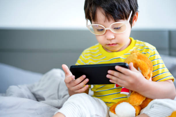 istock little boy using digital tablet or smart phones for playing games and watching cartoons, smart phone mobile addiction technology communication lifestyles. 1358386110