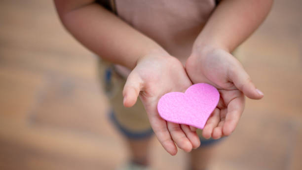 istock little boy hold heart. 1358387052