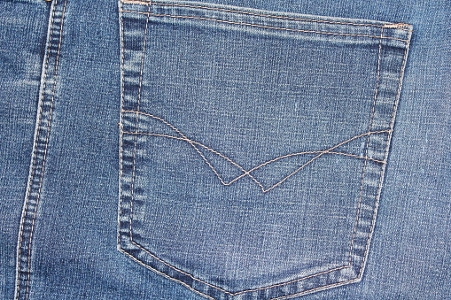 Blue jeans. Shabby denim. Back pocket. Background. Texture.