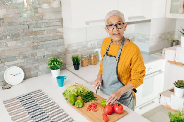 istock Senior woman preparing vegetarian dinner at her kitchen 1358395862