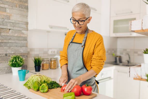 istock Senior woman preparing vegetarian dinner at her kitchen 1358395864