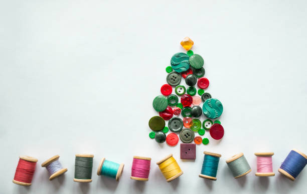 istock A Christmas tree made of buttons green, red color. Multicolored threads with wooden spools. White background, copy space. Creative Christmas concept 1358400201
