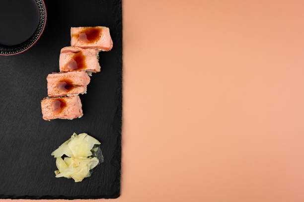 sushi rolls on stone serving board with soy sauce. above with copy space text. on pastel background.
