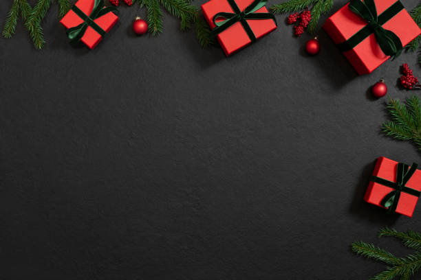 istock Christmas angle frame with wrapped gifts, fir branches and red decor on a black background. Christmas border. Happy New Year. View from above. Space for text. 1358400542