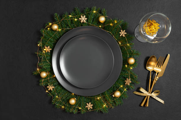 istock Christmas table setting with empty black plate, golden cutlery and a glass on a black background. New Year party. Copy space, top view, flat lay. 1358403638