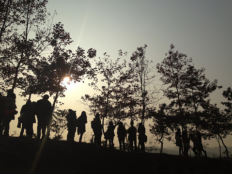 People walking on a trail enjoying sunset view in silhouette.