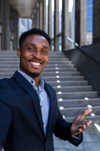 istock vertical view smartphone camera African American businessman speaks on phone using a front camera on a video call. Black business man talking on webcam. Conversation of an office worker in suit 1358406214