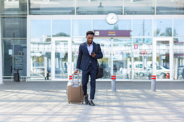 모바일 앱을 사용하여 택시를 호출하는 여행 가방과 함께 공항 근처여행 아프리카 사업가 - business suitcase men outdoors 뉴스 사진 이미지