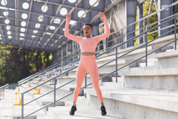 Woman doing burpee exercise, young African American woman doing fitness and active lifestyle in the morning, outdoors near the stadium Woman doing burpee exercise, young African American woman doing fitness and active lifestyle in the morning, outdoors near the stadium burpee stock pictures, royalty-free photos & images