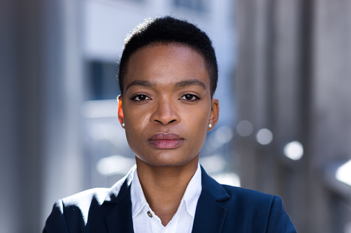 Headshot photo with close up portrait of serious businesswoman, african american woman confident and focused looking at camera