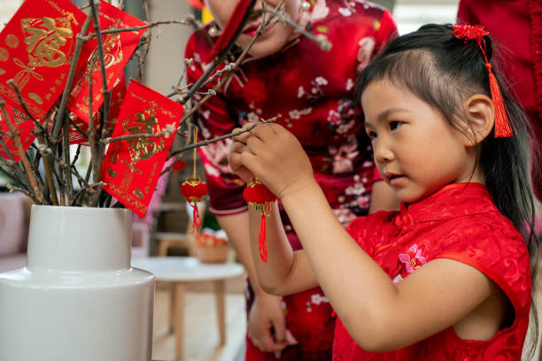 istock Cute little girl hanging decorative lanterns on branches 1358407941