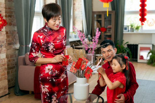 istock Young Chinese family of three decorating branches 1358407945