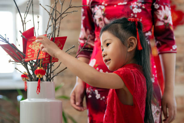 istock Cute little girl putting decorative lantern on branches 1358407948